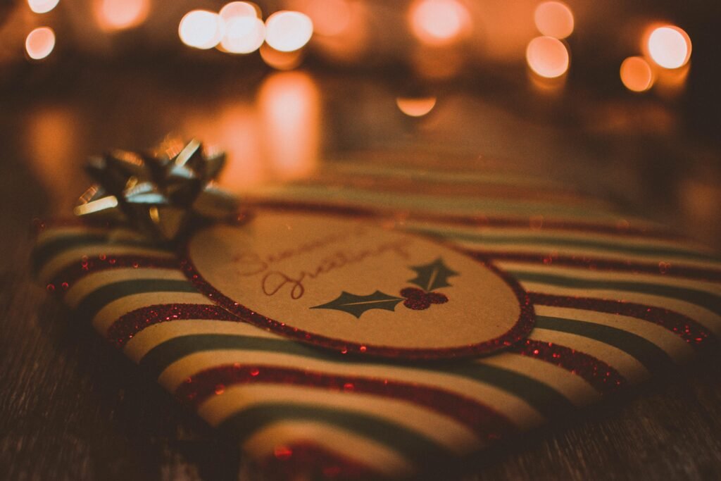 pexels-photo-1666513-1666513 Close-up of a Christmas gift with lights and festive wrapping, creating a warm holiday atmosphere.